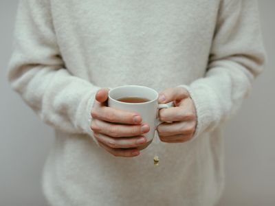 Hands holding a cup of tea in a calm setting